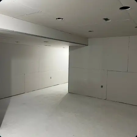 Long basement wall with drywall hung and ceiling pot lights cut in