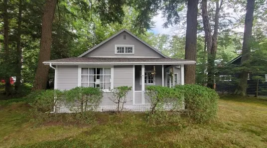 Freshly painted grey cottage with white trim among pine trees, a Heartmind exterior job